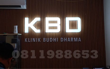 Huruf timbul akrilik LED KBD Klinik Budhi Dharma dengan efek backlit putih elegan di dinding kayu interior