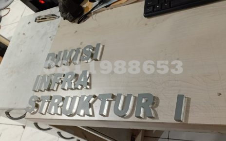 Huruf timbul akrilik custom tulisan DIVISI INFRASTRUKTUR untuk signage kantor dan papan nama gedung modern.