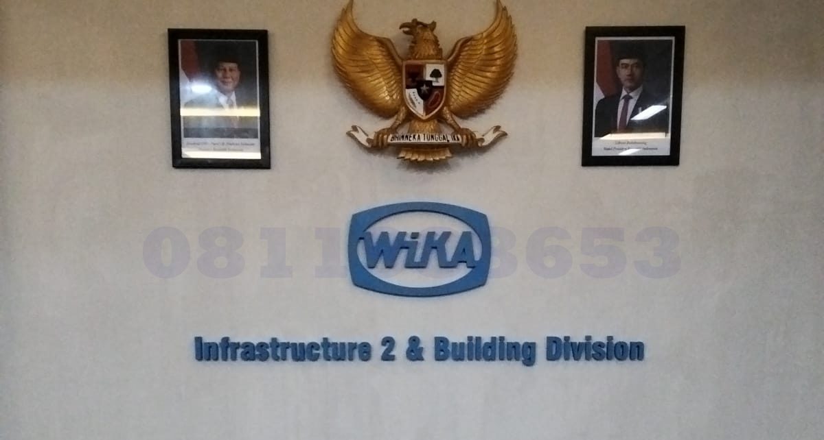 huruf timbul akrilik logo perusahaan WIKA di dinding kantor modern